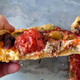hand holding slice of deep dish pizza